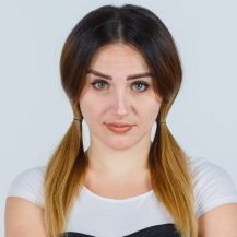 young girl standing arms crossed in white t-shirt, black dress and looking confident , front view.